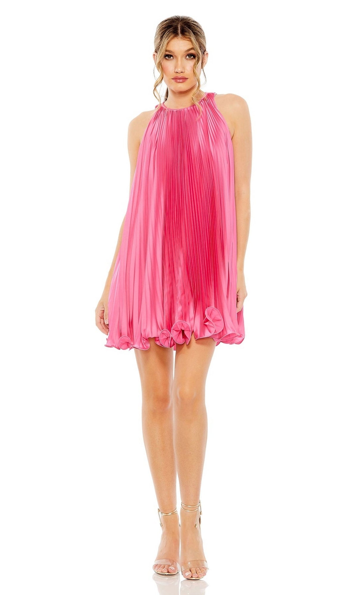 A woman wears the Mac Duggal 49636 short pleated semi-formal dress in hot pink with a high neck and ruffled hem, paired with strappy heels—a chic cocktail look for any stylish event.